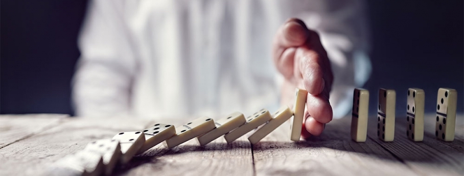 Personne qui arrête des dominos en train de tomber avec sa main