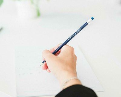 personne qui tient un crayon bleu avec écrit highlight dessus